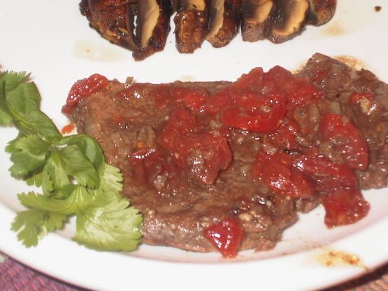 meat with sauce and garnish on a white plate next to some parsley