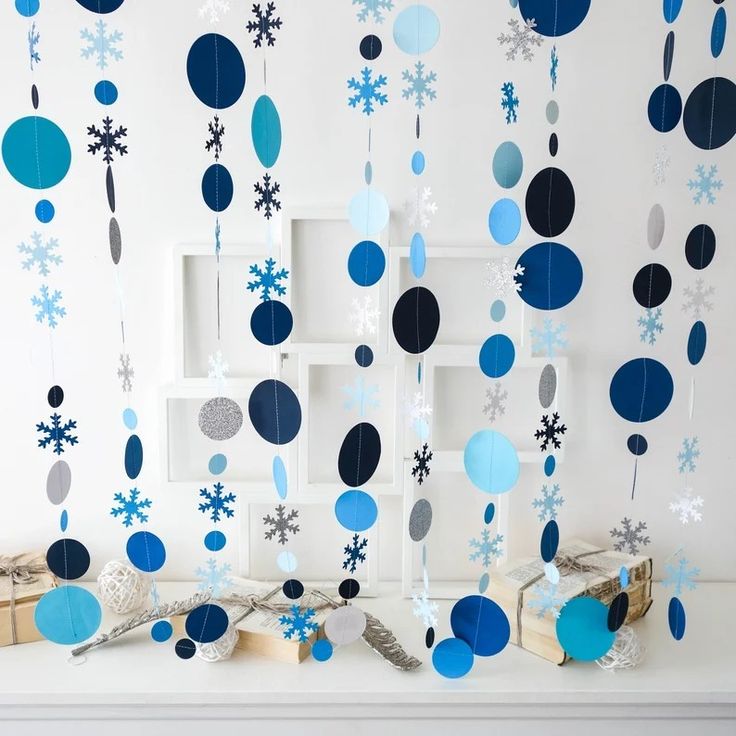 blue and white decorations hanging from the ceiling in front of a wall with snowflakes