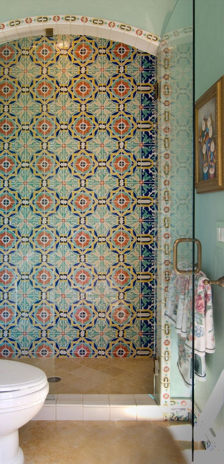 a bathroom with a toilet, shower and tiled walls