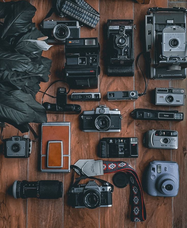 many different types of cameras on a wooden floor