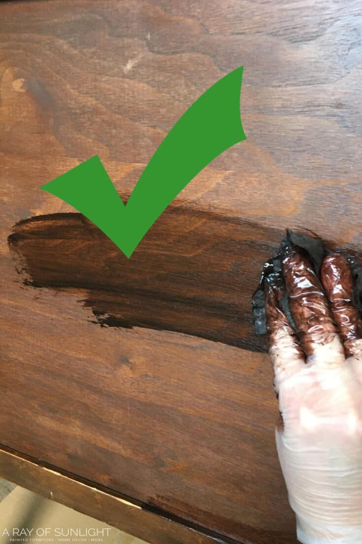 a person with their hand on the edge of a wooden table that has been stained green