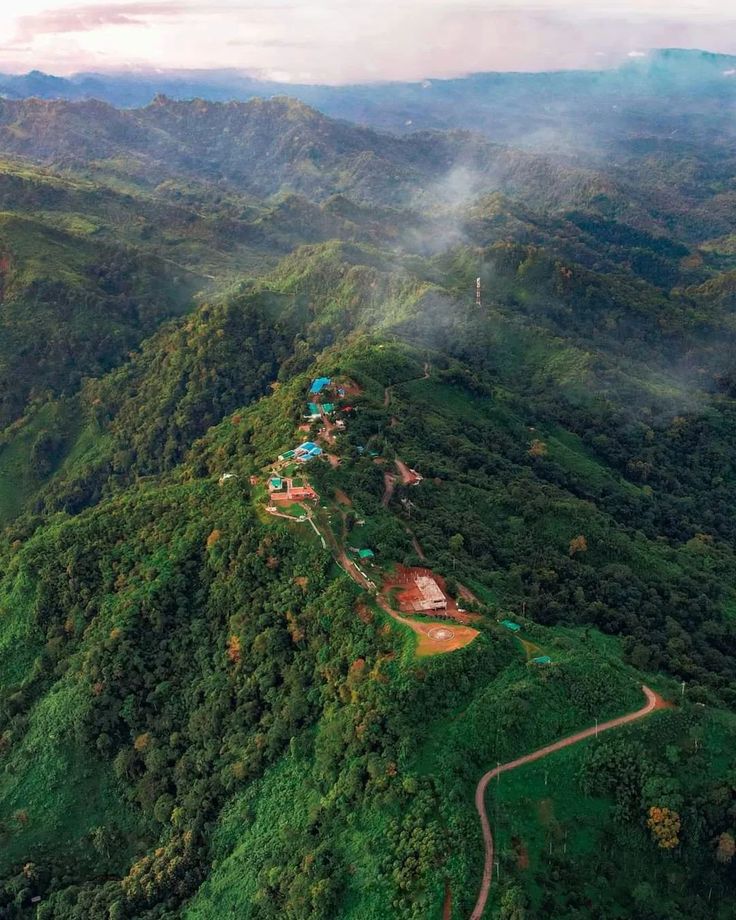 an aerial view of a lush green mountain range with lots of trees and houses on it