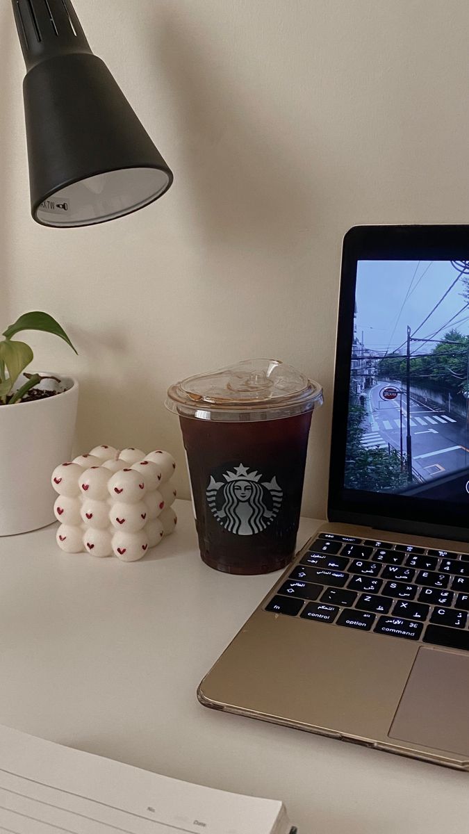 an open laptop computer sitting on top of a desk next to a cup of coffee