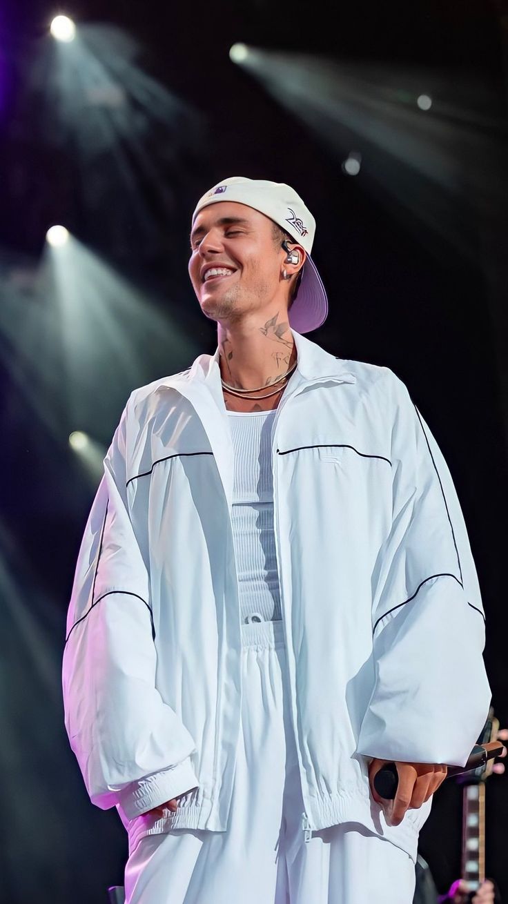 a man standing on top of a stage wearing a white outfit