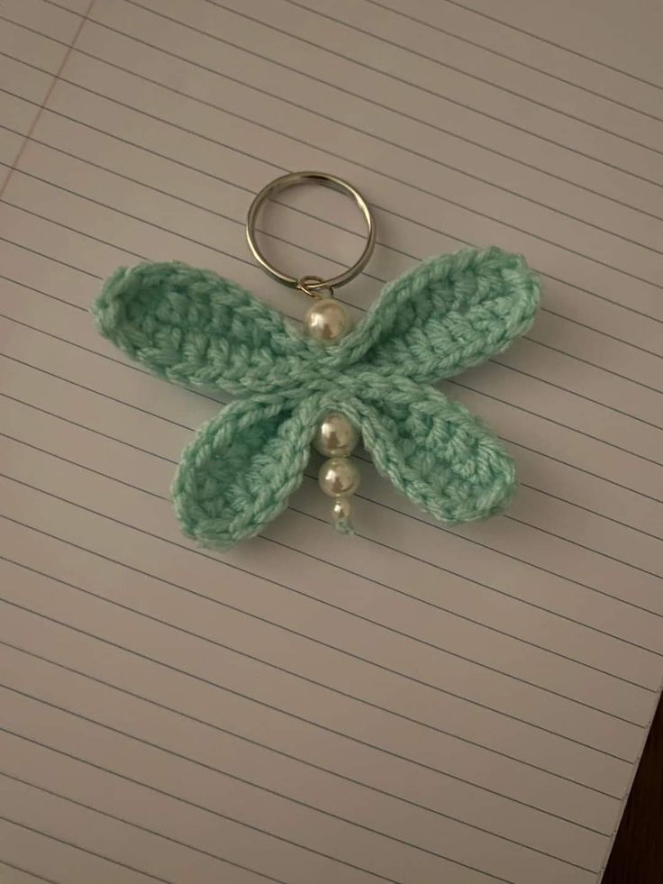 a crocheted key chain with a flower attached to it on top of lined paper