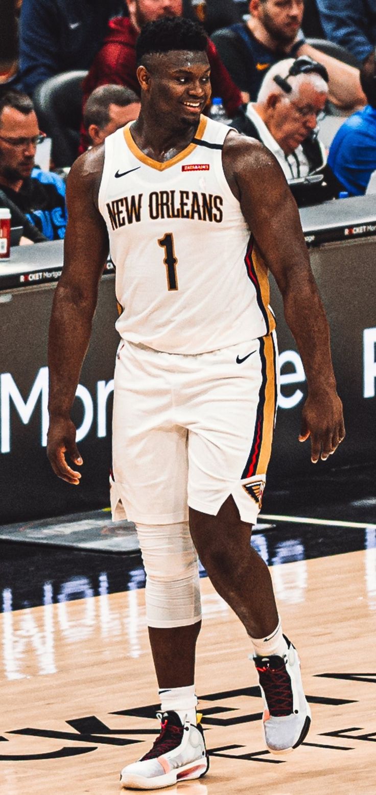 a basketball player is walking on the court with his shoes off and people in the stands watching