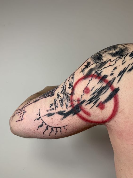 a man's arm with red and black ink on it, in front of a gray background