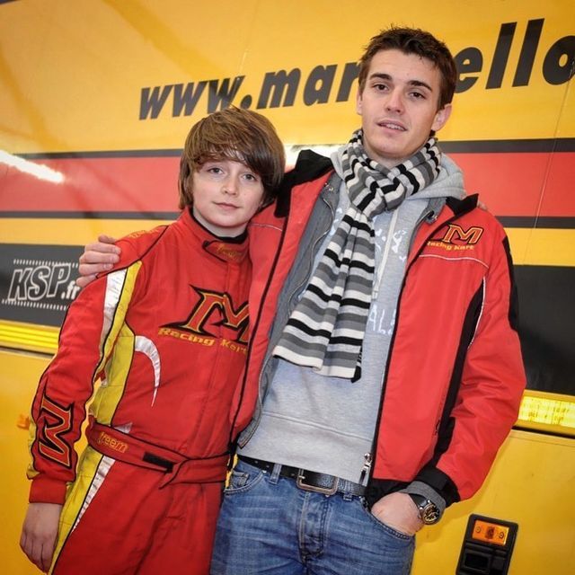 two people standing next to each other in front of a bus