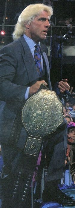 a man in a suit and tie holding a wrestling belt