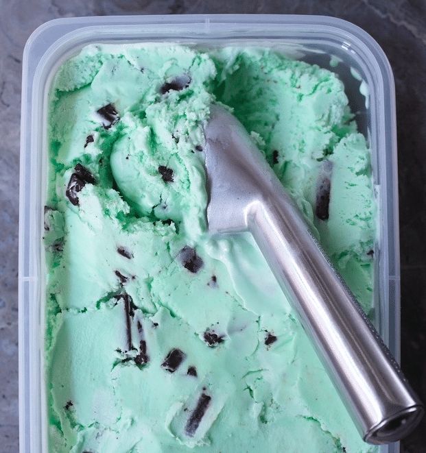 an ice cream container with mint green chocolate chip ice cream and a scoop of ice cream