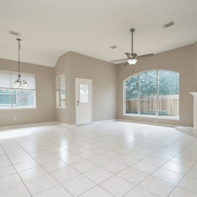 an empty living room with tile flooring and two windows in the middle of it