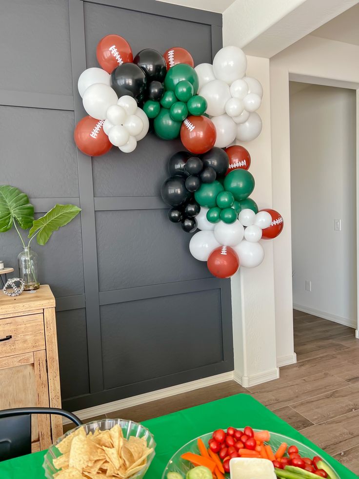 a football themed party with balloons and food on the table in front of a door