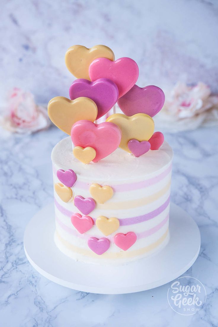 a white cake with pink, yellow and purple hearts on top