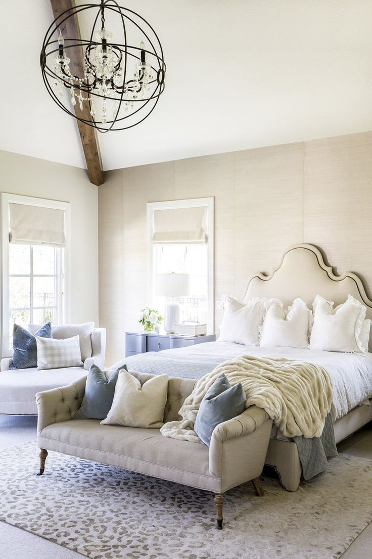 a bedroom with a bed, chair and chandelier hanging from it's ceiling