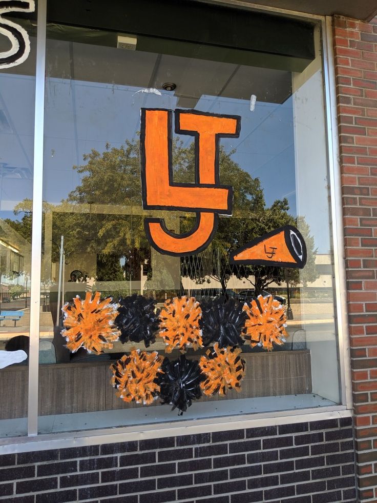 the front window of a store with orange and black decorations on it's windowsill