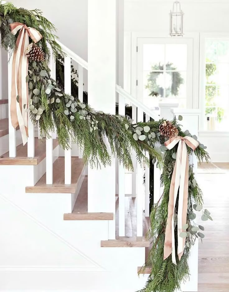 the stairs are decorated with greenery and pine cones for garlands on each handrail