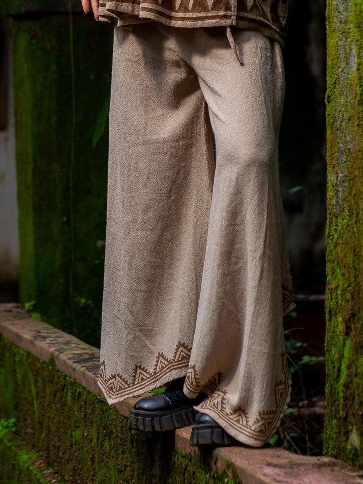 Get ready to embrace your bohemian side with our Sakhi Pants! These stylish pants feature an asymmetrical bottom hem and a unique block print on the bottom side. With a free size, they're comfortable for all body types. Plus, they're sustainably made for guilt-free fashion. Perfect for the free-spirited fashionista! Get ready to strut your stuff in style with the Sakhi Pants! With these statement pants, you'll be turning heads wherever you go. (So, go ahead and buy it!) Switch up your wardrobe g Bohemian Embroidered Beige Bottoms, Beige Bohemian Embroidered Bottoms, Embroidered Wide-leg Beige Pants, Embroidered Wide Leg Beige Pants, Embroidered Beige Wide Leg Pants, Hippie Style Brown Bottoms For Festival, Hippie Style Brown Festival Bottoms, Brown Hippie Bottoms For Festival, Bohemian Wide Leg Pants For Vacation