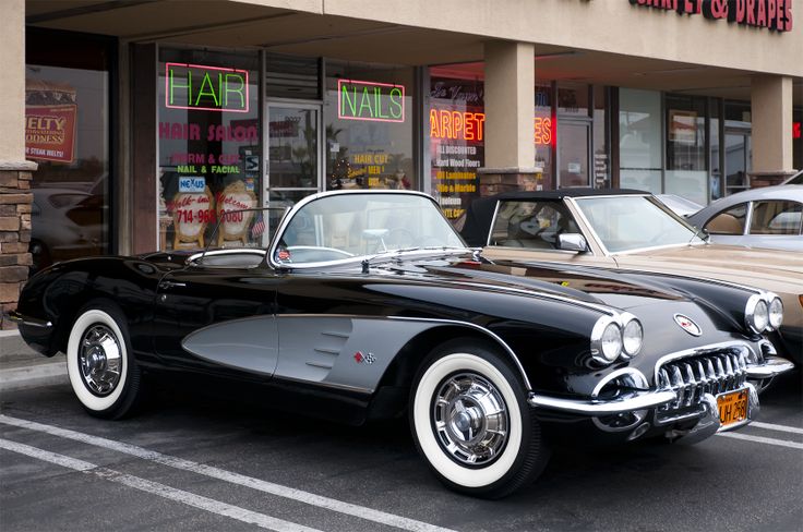 two classic cars parked in front of a store