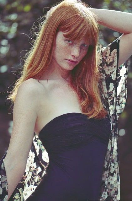 a woman with red hair wearing a black dress