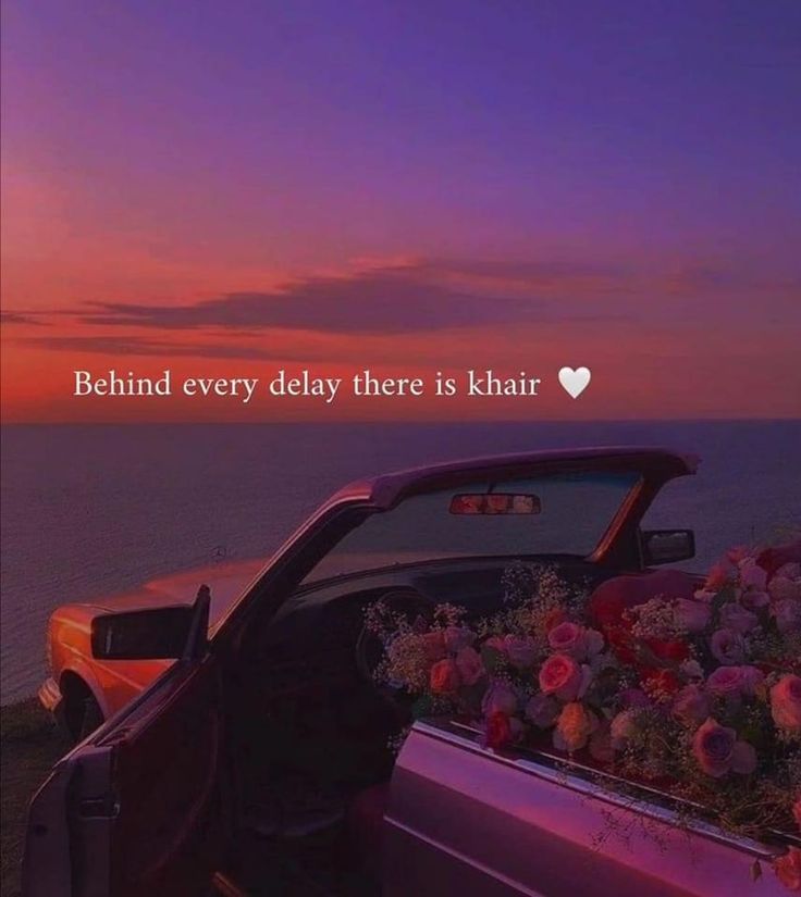 a car parked next to the ocean with flowers in the bed and a quote on it