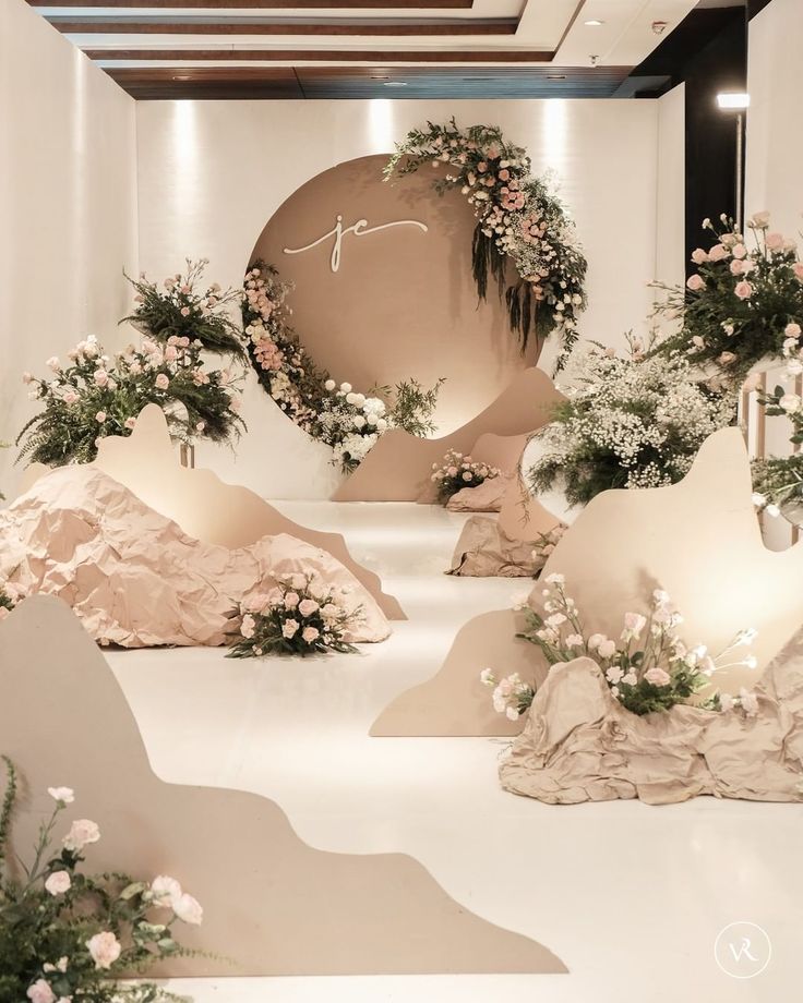 a white room with flowers and rocks on the floor, in front of a circular sign that says love