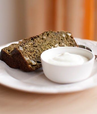 a piece of bread on a white plate with a bowl of yogurt next to it