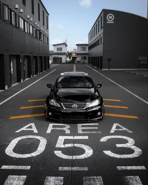 a black car parked in the middle of an empty parking lot