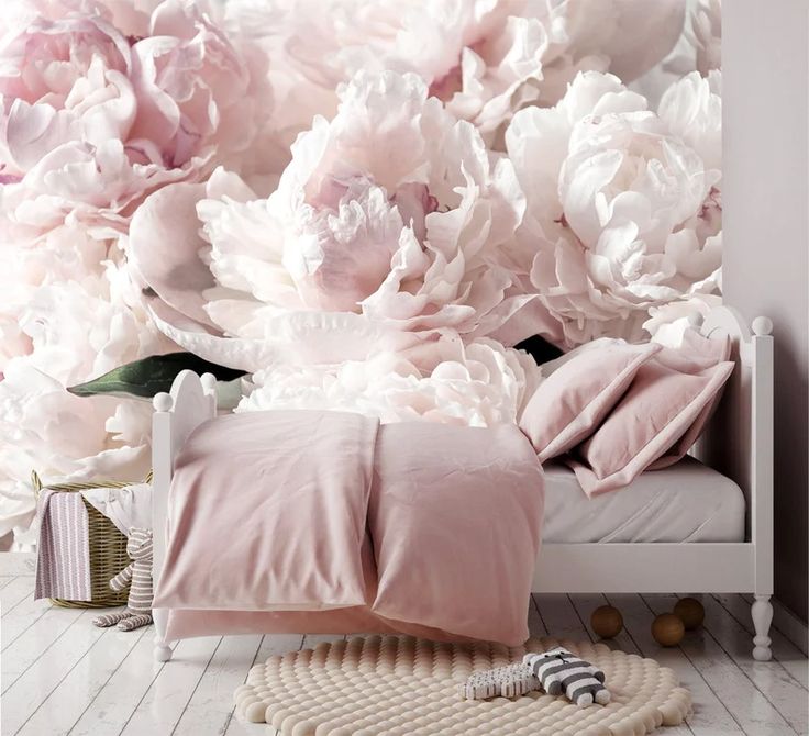 a bedroom with pink flowers on the wall and white bedding in front of it