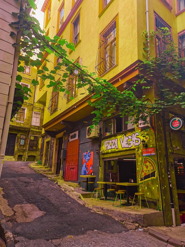 a yellow building with graffiti on the side and trees growing out of it's windows