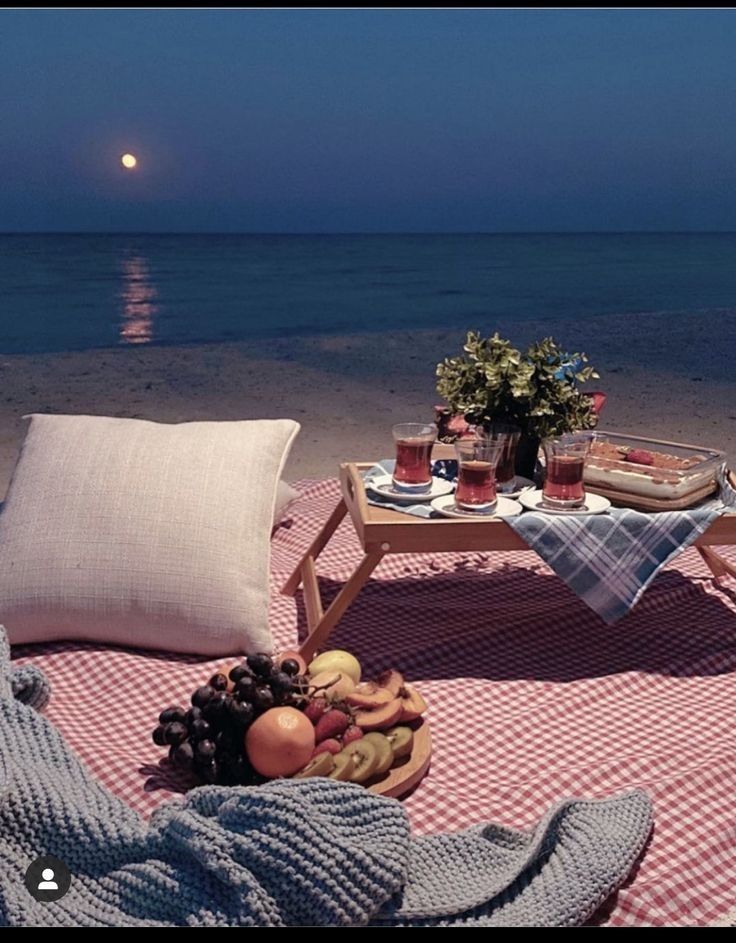 a picnic on the beach is set up with food and drinks in front of the ocean