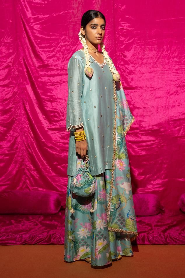 Mint chanderi silk kurta with sequin, pearl placement embroidery. Paired with floral print sharara and fringe bordered dupatta.
Components: 3
Pattern: Printed, Embroidery
Type Of Work: Floral, sequin, pearl
Neckline: Scallop V neck
Sleeve Type: Long sleeves
Fabric: Chanderi Silk, Lining: Shantoon
Color: Green,Blue
Other Details: 
Fringe tassel bordered dupatta
Length:
Kurta: 35 inches
Sharara: 38 inches
Note: Potli shown in the image is not for sale
Occasion: Sangeet - Aza Fashions Embroidered Silk Floor-length Sets, Floor-length Embroidered Silk Set, Festive Cotton Silk Palazzo Set With Dupatta, Raw Silk Cutdana Unstitched Sets, Designer Cotton Silk Palazzo Set With Dupatta, Chanderi Palazzo Set With Gota Work, Floor-length, Floor-length Chanderi Palazzo Set With Gota Work, Silk Sets With Resham Embroidery For Navratri, Bollywood Silk Set With Zari Work