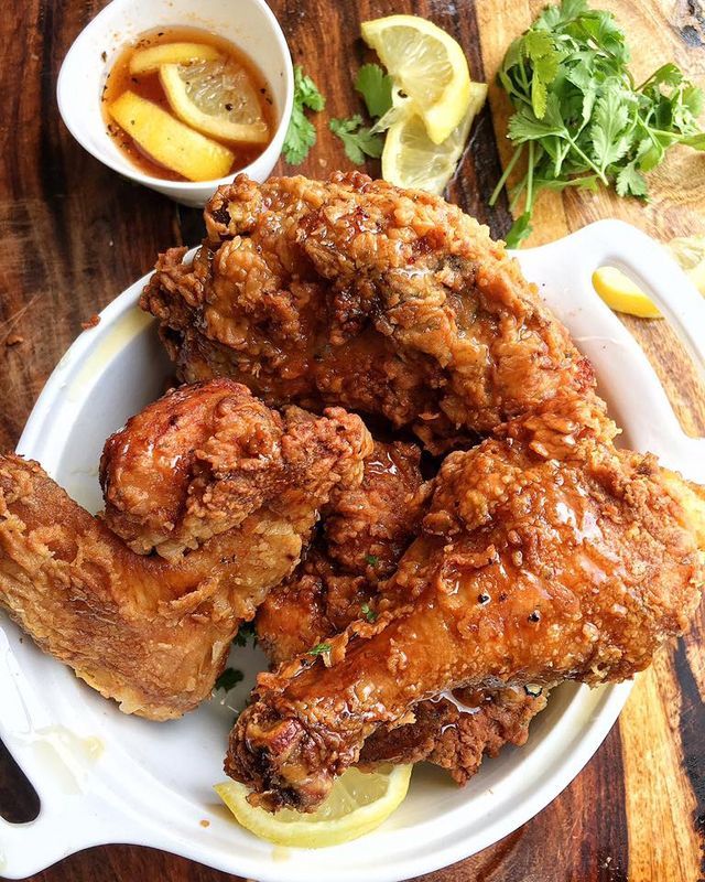 fried chicken on a plate with lemon wedges and sauce