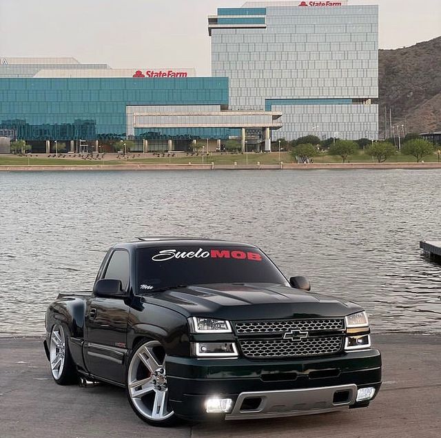 a black truck parked in front of a body of water next to a large building