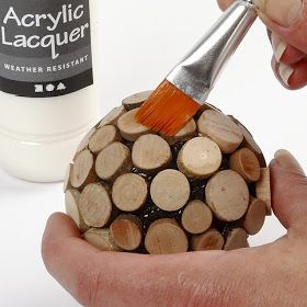 a person is holding a paintbrush over a ball of firewood that has been cut into smaller pieces