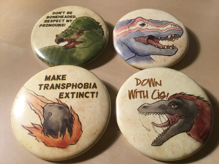 four buttons with dinosaurs on them that say make transopia extinct and don't be domestic