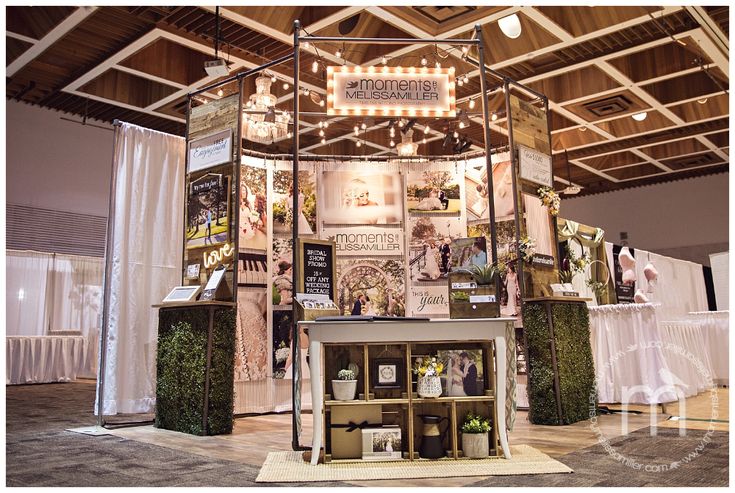 a booth with lights and pictures on the wall, in an indoor event venue at night