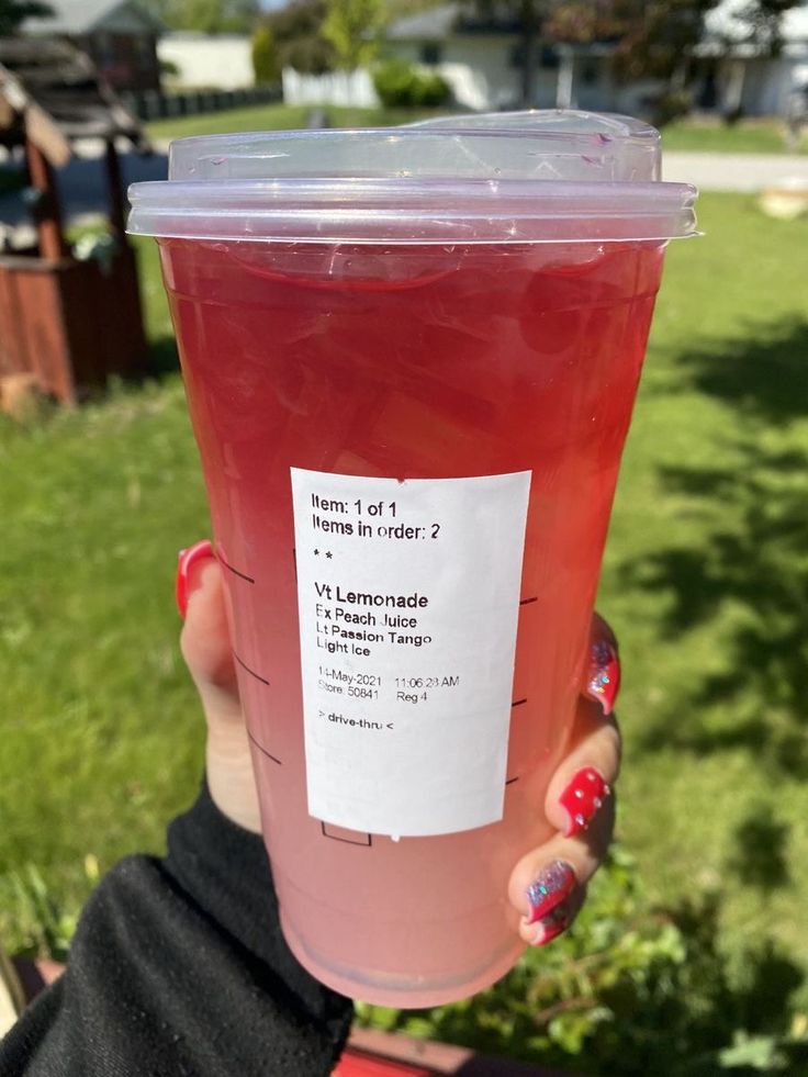 a person holding up a plastic cup filled with liquid