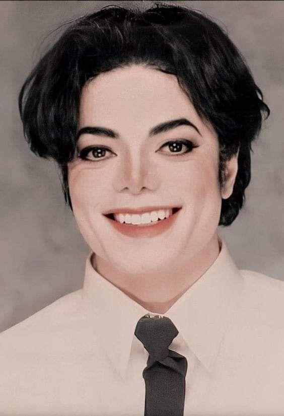 a woman with short hair wearing a white shirt and black tie smiling at the camera