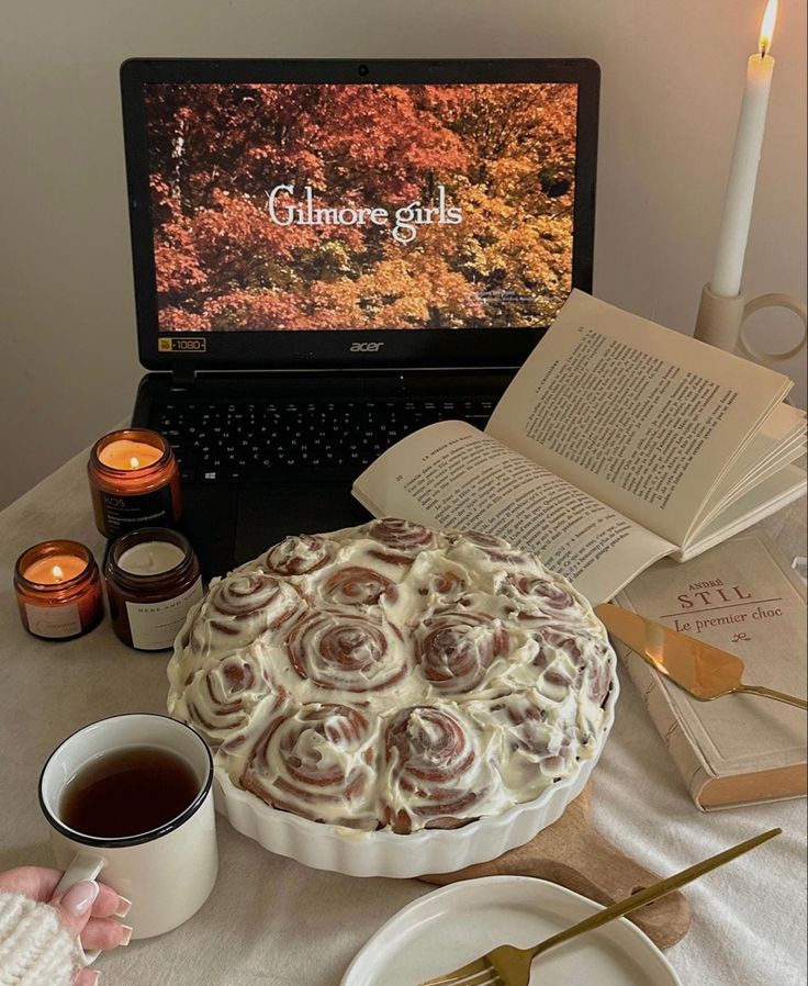 a cake sitting on top of a table next to an open book and coffee cup