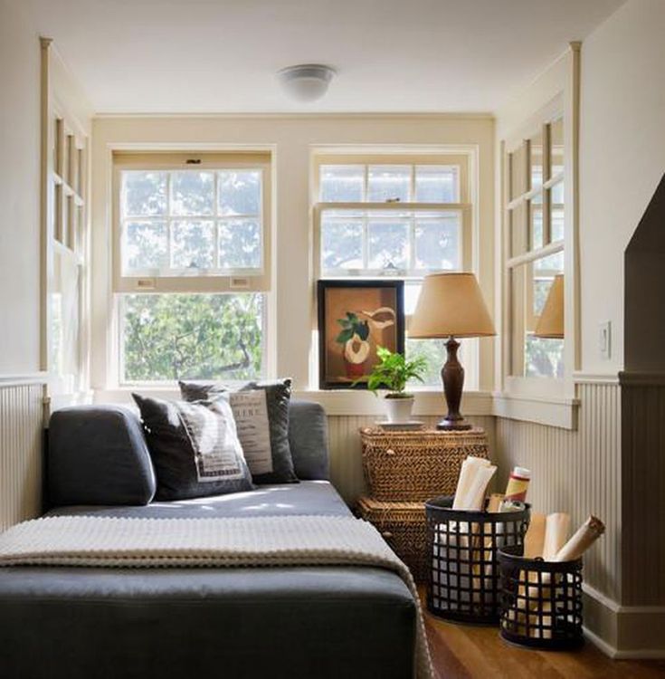 a living room filled with furniture next to two windows and a lamp on top of a table