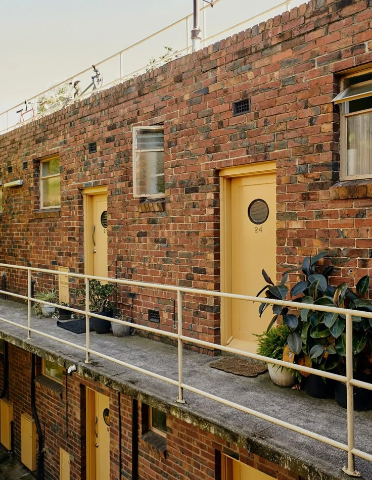 a brick building with potted plants on the balcony