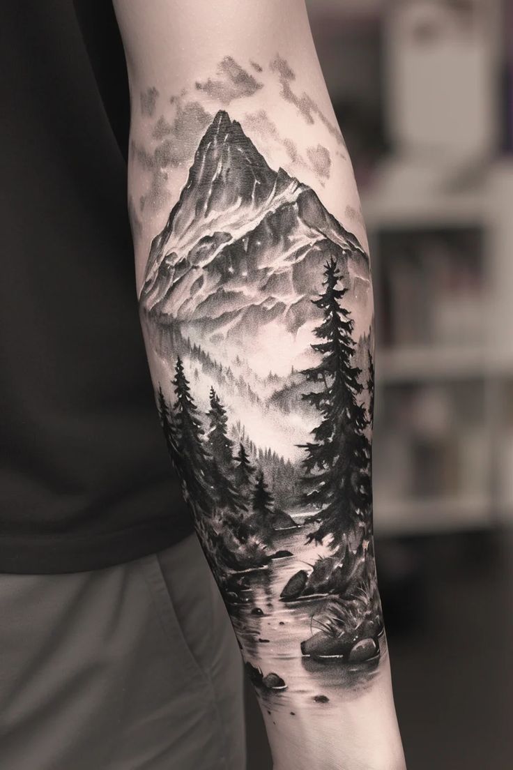 a man with a mountain and forest tattoo on his arm