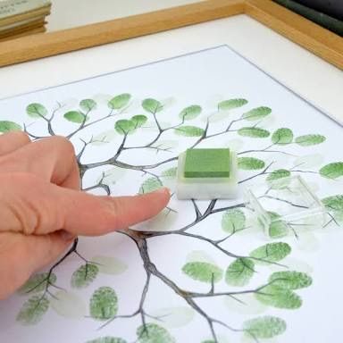 a person's hand is touching a stamp on a tree print with green leaves