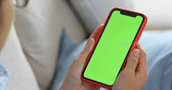 a person holding a cell phone with a green screen in their hands - stock photo - images