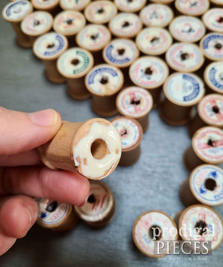 a person holding a wooden object in front of many small donuts on a table