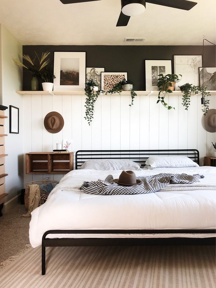 a white bed sitting in a bedroom next to a wall with pictures hanging on it