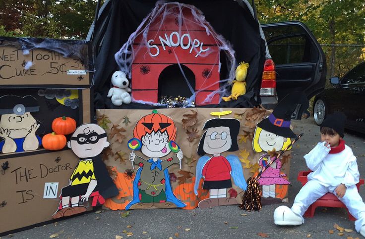 a child sitting on the ground next to some cardboard cut outs with cartoon characters painted on them