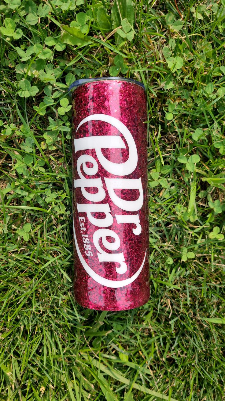 a can of coca - cola sitting in the grass