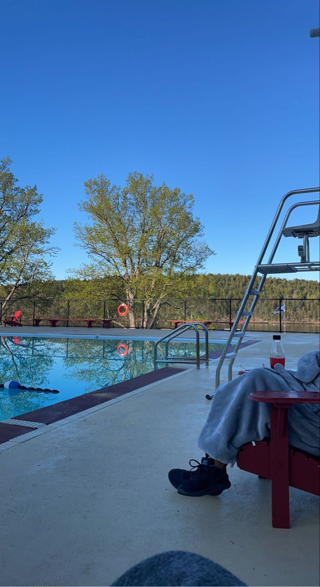 a man sitting on a red bench next to a swimming pool with a slide in the background