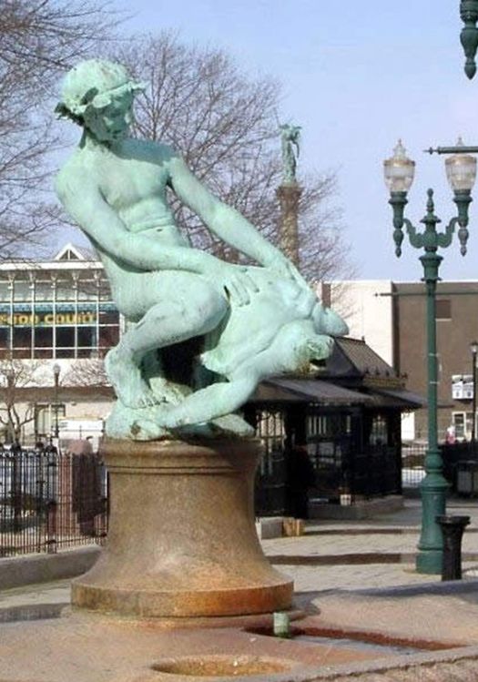 there is a statue in the middle of a plaza with street lights and buildings behind it